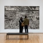Visitors inside the Blanton Museum of Art looking at a large, very detailed black/white mural titled 