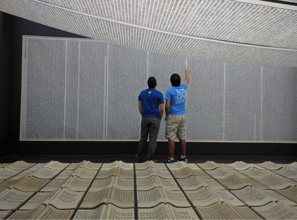 two patrons looking and pointing at scrolls in the exhibition Xu Bing: Book from the Sky