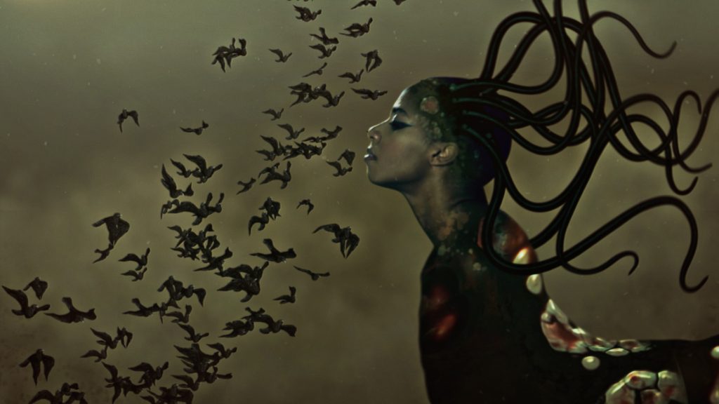 Wangechi Mutu, The End of eating Everything (video still). Strange figure with a womans face and flowing snake like hair, in front of her are a swarm of birds