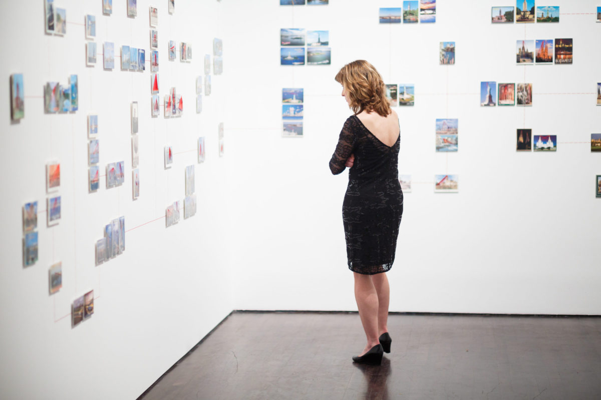 Woman looking at postcards on a white wall.