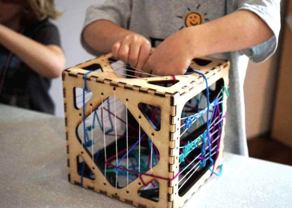 detail view of a visitor interacting with one of the boxes from Mindful Weaving