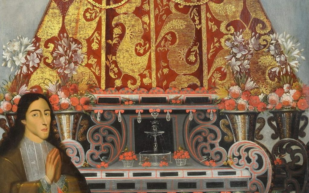 close up of the donor with his hands in prayer at the bottom of the lady of bethlehem statue. the bottom of the statue is ornate and surrounded with baskets and vases full of fresh flowers