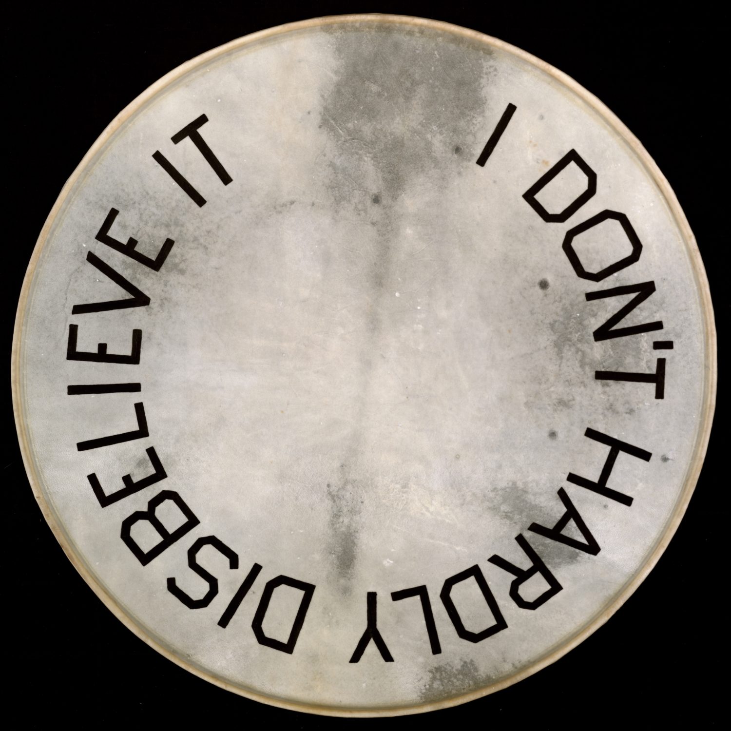 Artwork by Ed Ruscha, a drumskin head with "I Don’t Hardly Disbelieve It" painted on it