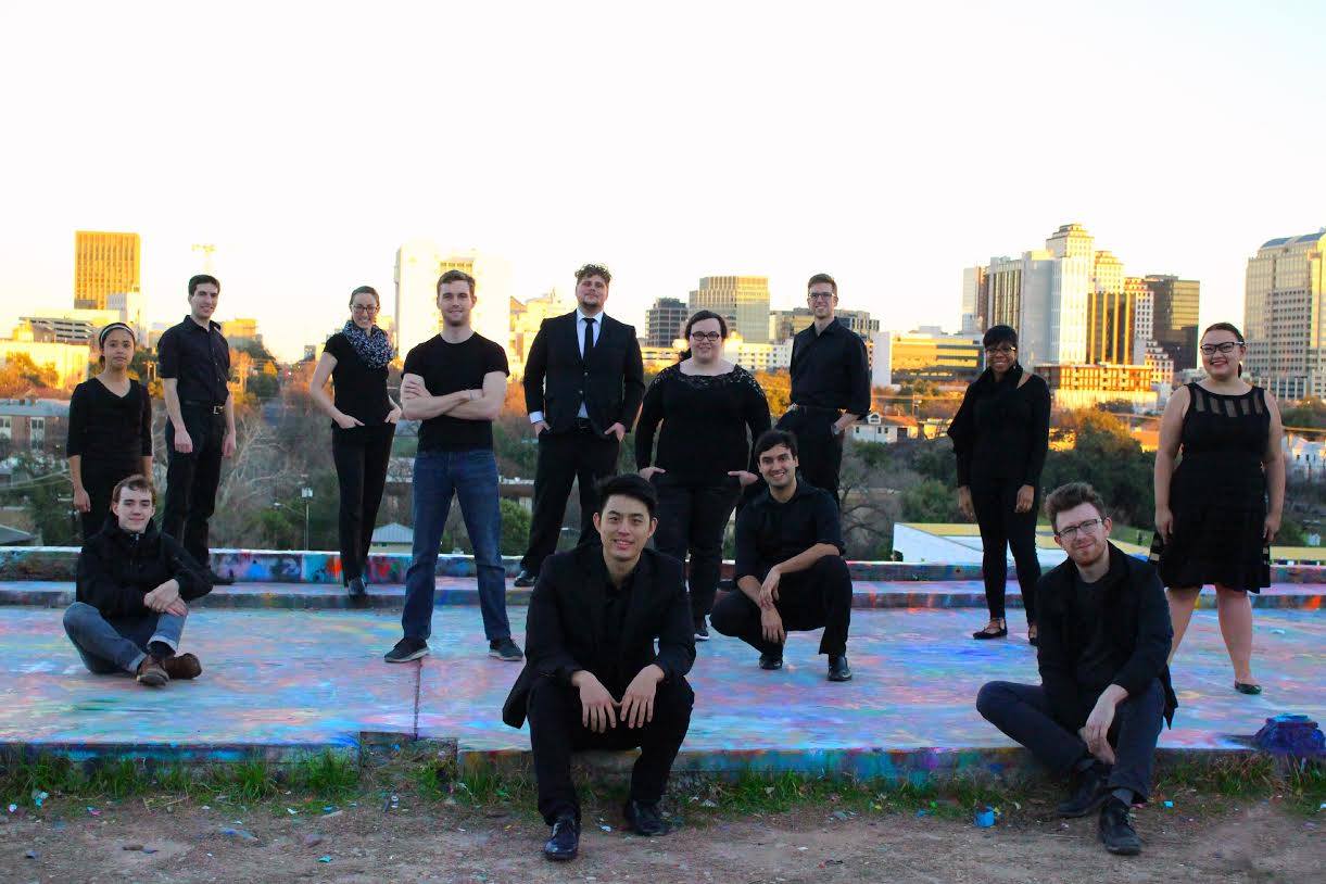 Group of young adults wearing black with the Austin skyline behind them.