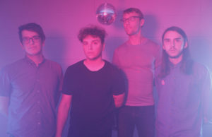 four men in a purple lighted room with a disco ball in the middle