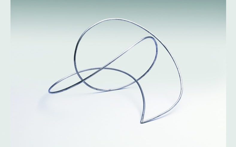 Photo of "La Linea Continua (Continuous Line)" by Enio Iommi a sculpture where a stainless steal bar loops around and through itself before connecting to a point a the base