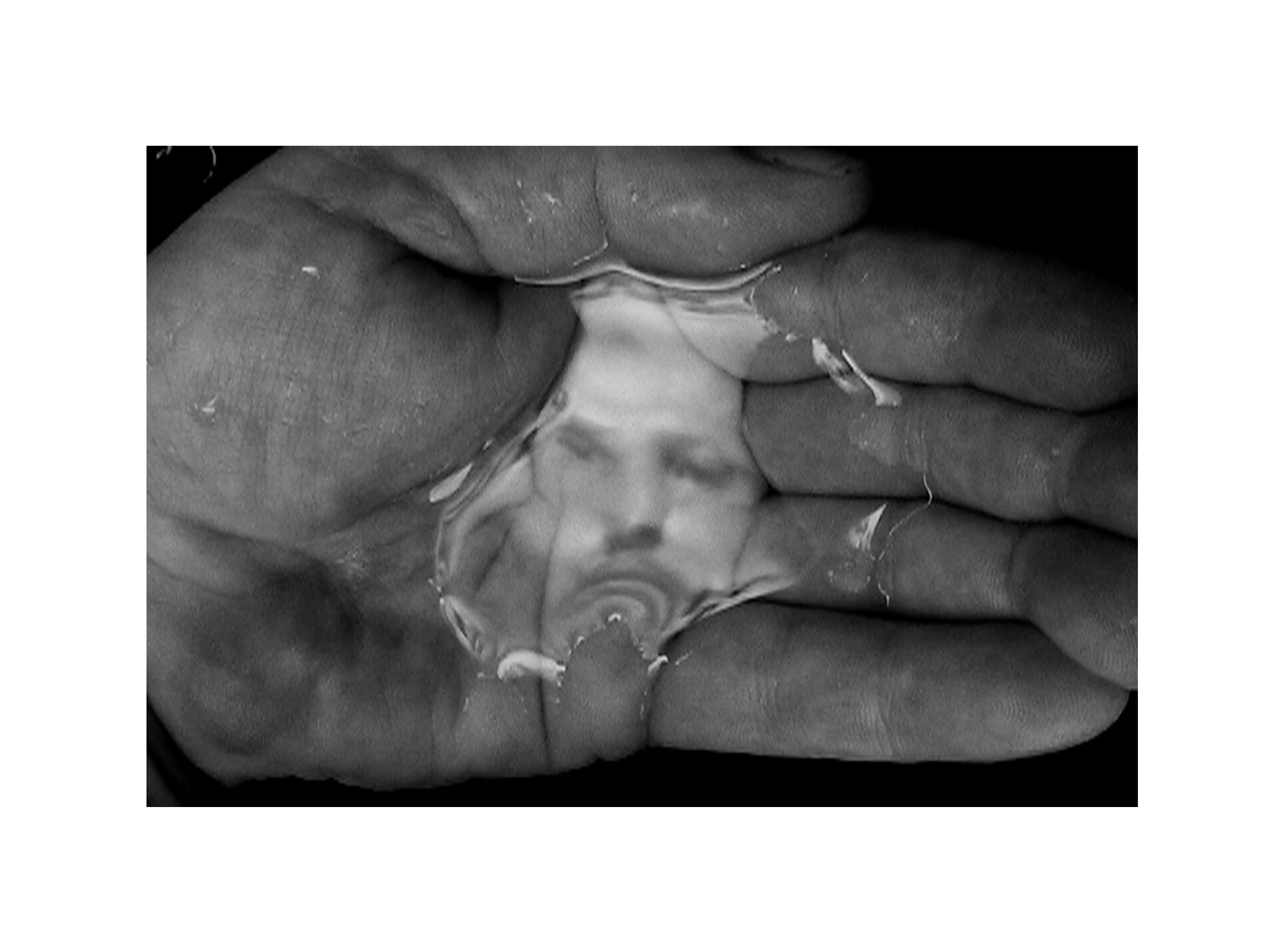 A hand holding some water which casts a reflection of a man's face.