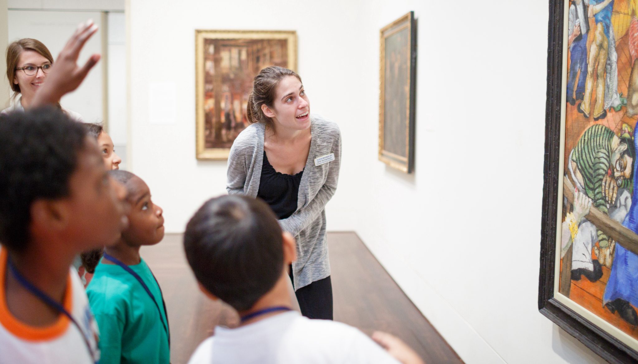 A gallery teaching looking at a painting with some young children inside an art museum