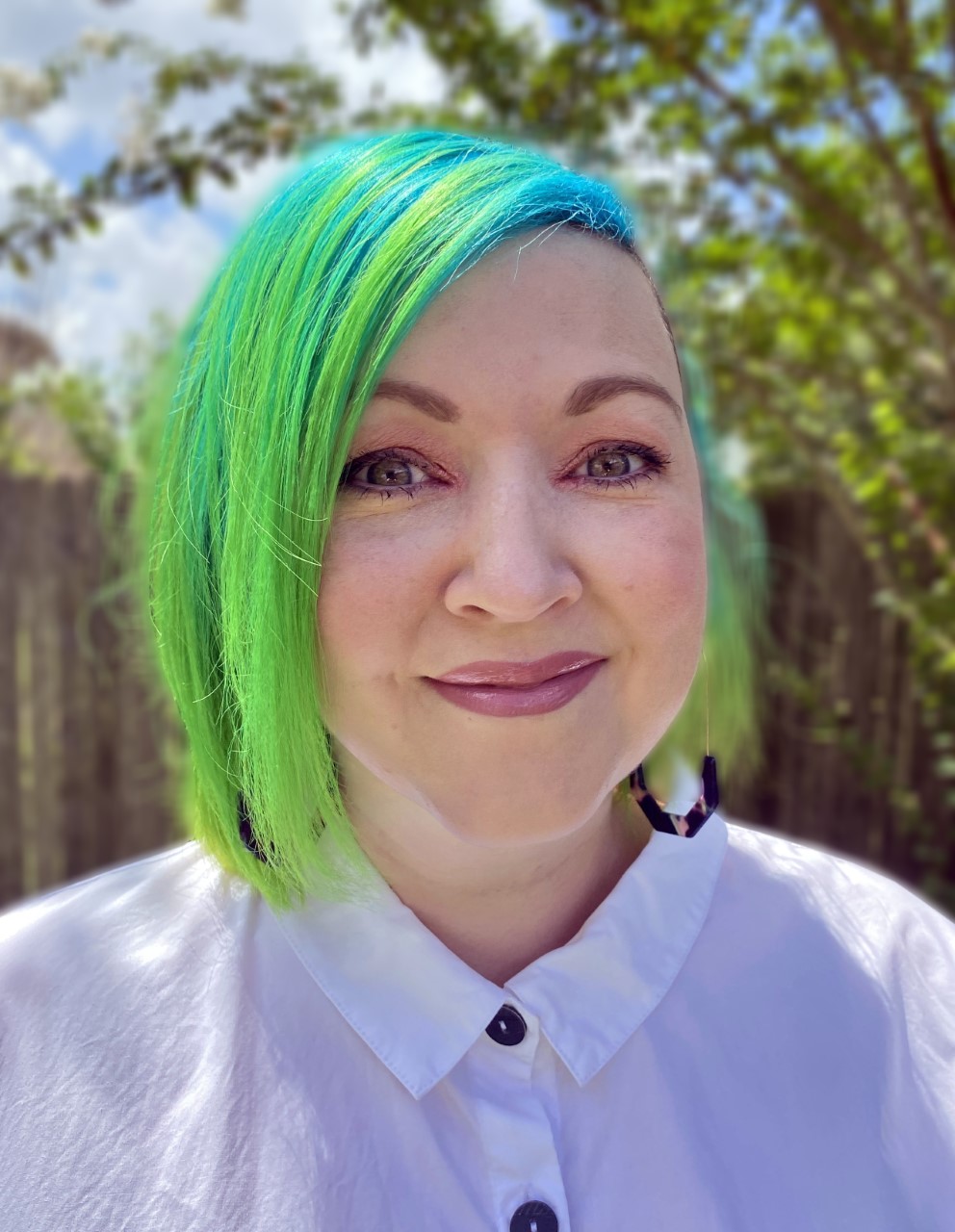A headshot of a woman with short bright green hair