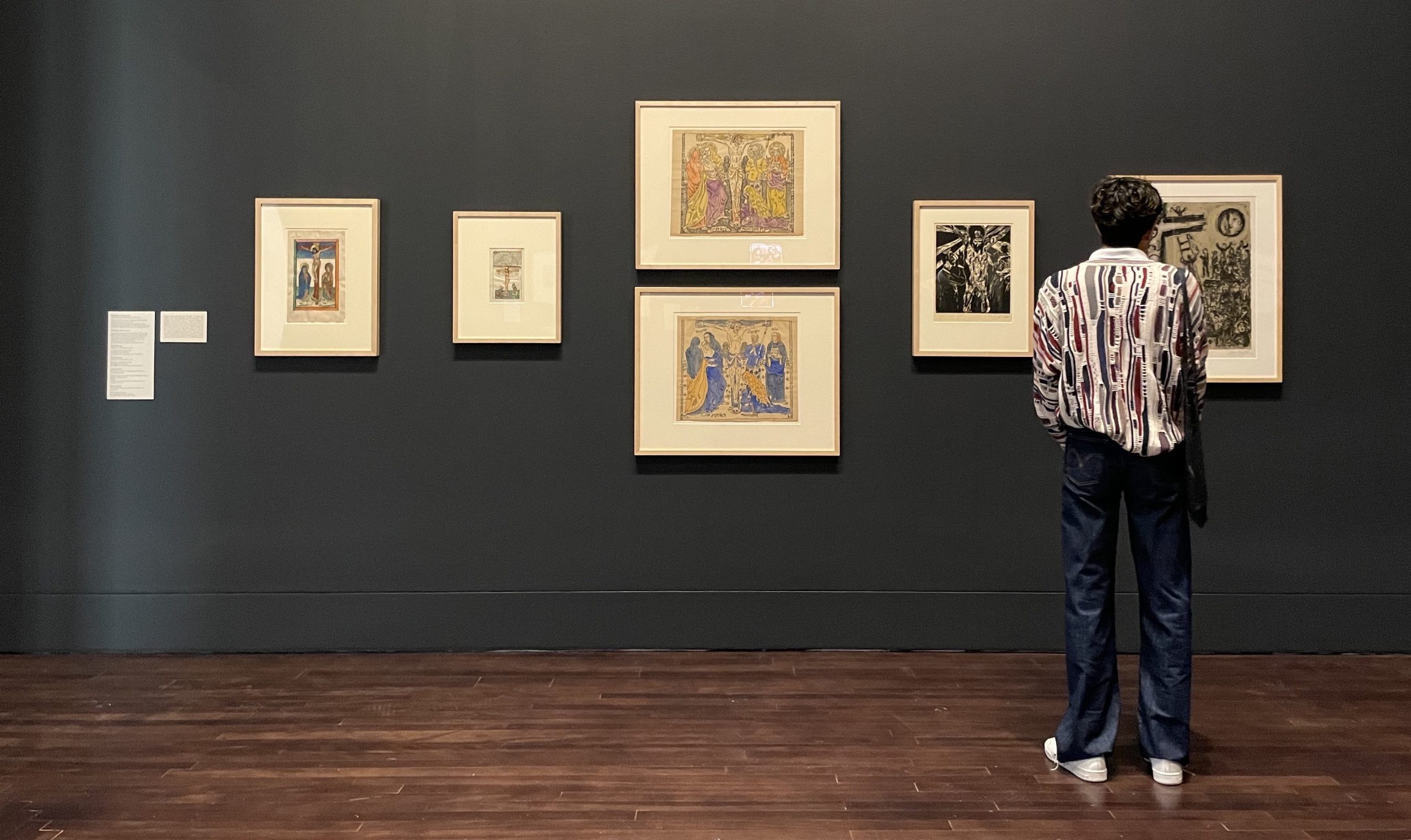 A person looking at various medieval framed prints on a wall