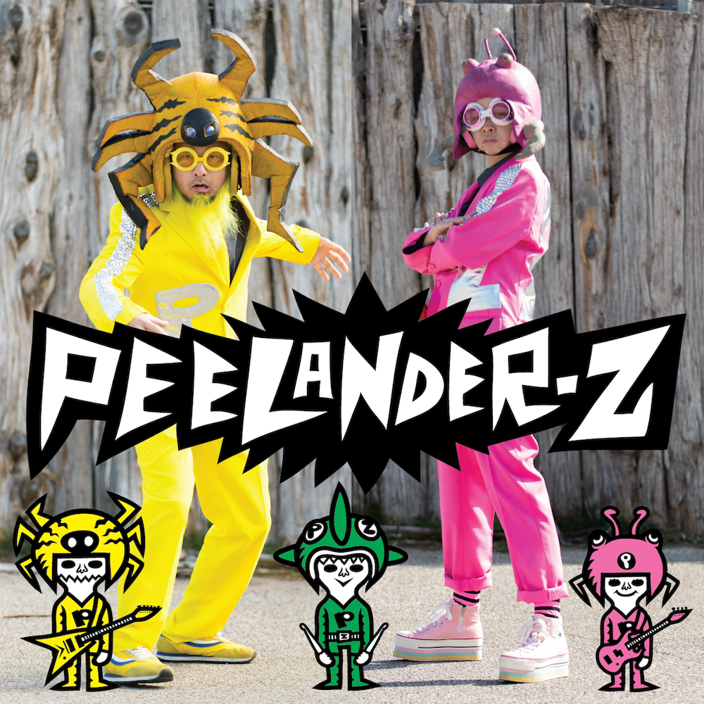 Two people, one in full yellow and a crab hat, the other all in pink with a pink hat, posing with the name "Peelander-Z" as a graphic at the front