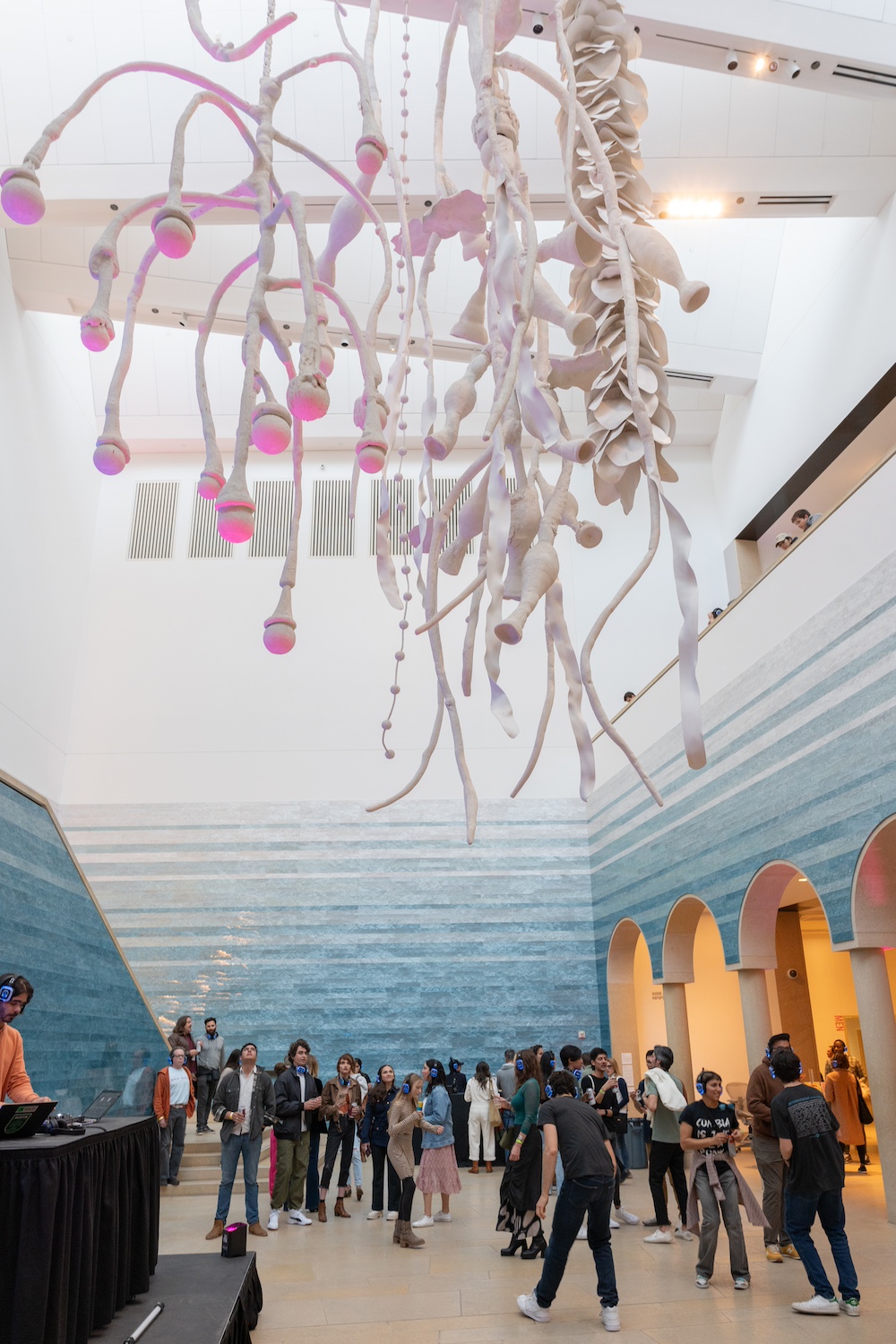 A DJ set in the atrium of the Blanton Museum of Art. Lots of people are standing and dancing while wearing headphones