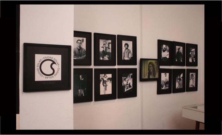Una pared blanca con retratos en blanco y negro de personas, colgados en la pared.
