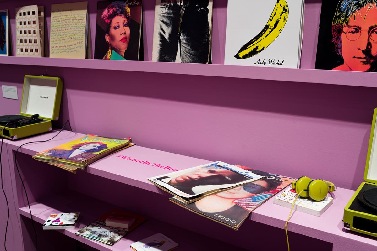 Vinyl album covers displayed on a shelf above a book case with several magazines displayed on top in the resource room
