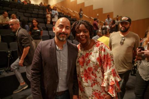 Vincent Valdez and Yulanda McCarty-Harris posing together in front of the auditorium seating. There are a few people in the background.