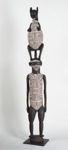 Sculpture of a human type figure with an animal on their head both bodies are covered in an intricate pattern