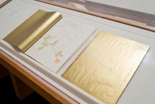 Printed books featuring illustrations using gold leaf embellishments in a display case