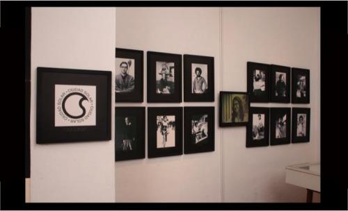 A white wall with black and white portraits of people, hanging on the wall.