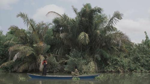 a blindfolder woman in a boat on a tropical-looking river